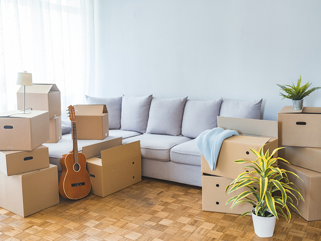 Moving day concept, cardboard carton boxes stack with household belongings in modern house living room, packed containers on floor in new home, relocation, renovation, removals and delivery service